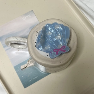Pince à cheveux coquillage bleu clair avec nœud rose et perles sur fond de plage