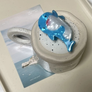 Gros plan d'une pince à cheveux dauphin bleue et blanche en acétate nacré élégante