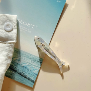Dettaglio del fermaglio per capelli in acetato a forma di pesce con finitura perlata