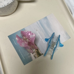 Détail de la pince à cheveux rose en forme de coquillage et pince en acrylique bleu