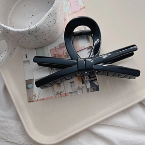 Macro detail of glossy black bow hair claw clip with strong metal spring mechanism