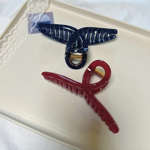 Detail view of large navy and burgundy hair claws with gold springs in a stylish tray
