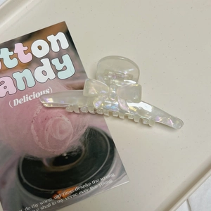 Iridescent white acetate bow hair claw clip for women in a 45-degree aesthetic view