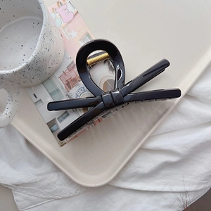 Detail shot of a large black glossy bow hair claw clip showing a strong metal spring