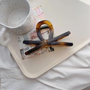 Detail of elegant tortoiseshell bow hair claw clip on a stylish cream jewelry tray