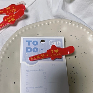 Red airplane hair clips with Chinese patriotic slogans in a ceramic dish