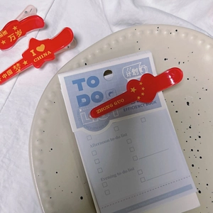 Detail shot of red acrylic hair clips with Chinese patriotic motifs on a beige plate