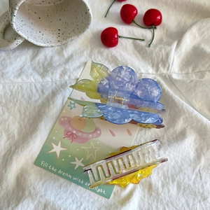 Detailed view of large marble floral hair claw clips on white fabric with artistic decor