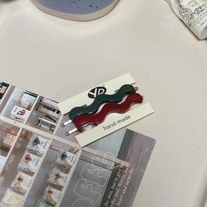 Detail of handmade wavy hair clips in dark green and burgundy red on card holder