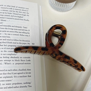 Pince à cheveux élégante de 12,5 cm à motif léopard écaille de tortue sur un livre ouvert