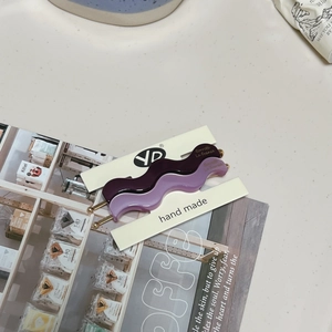 Close-up of wavy purple acetate hair clips on display card with handmade branding