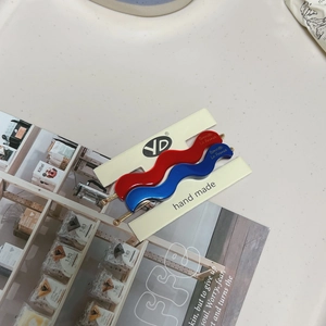 Matte wavy hair clips in red and blue colors displayed on a premium lifestyle background
