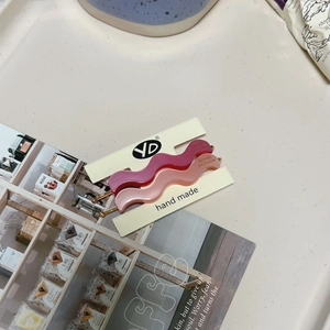Matte wavy acetate hair clips in pink and magenta colors on a branded display card