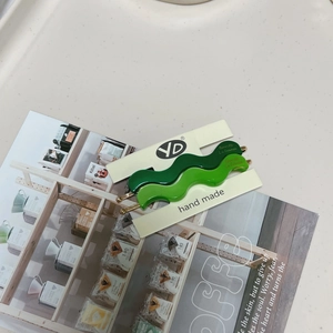 Chic wavy matte hair clips in green and mint shades on an elegant marble surface