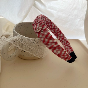 Close-up of red and white checkered woven headband with alo logo on a ceramic cup