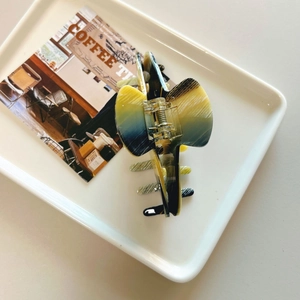 Detail of elegant acetate hair claw clip with blue and yellow marble pattern texture