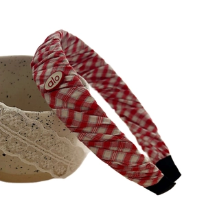 Red and white checkered fabric headband featuring a branded oval plaque and non-slip ends
