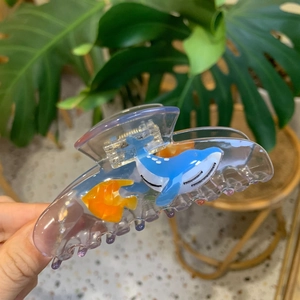 Detail of transparent purple claw clip with blue whale and orange fish decorations