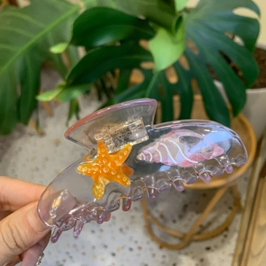 Detail of purple acetate hair claw clip with starfish and seashell patterns