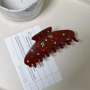 Vintage caramel acetate hair claw clip with crystal cherry pattern on marble background