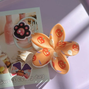 Detail of orange floral Halloween hair claw featuring pumpkin, ghost and bat patterns