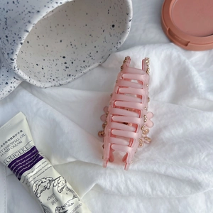 Détail d'une pince à cheveux fleur rose givré avec strass sur fond de tissu blanc doux