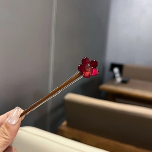 Vue détaillée d'une élégante épingle à cheveux en bois de rose avec fleur rouge translucide
