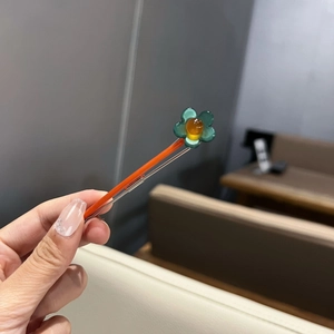 Détail d'une pince à cheveux à nœud floral avec pétales orange et accents de feuilles