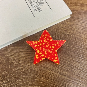 Star-shaped red and yellow acetate hair claw clip handcrafted on a wooden table