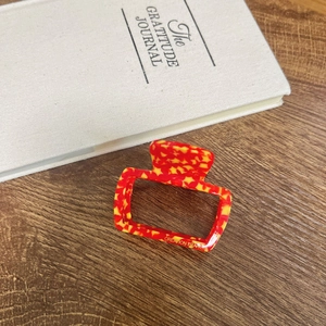 Detail of red and yellow star hair claw clip with Creation France lettering on wood