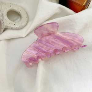 Pink and purple marble hair claw clip with subtle glitter on white textured fabric