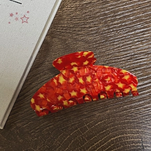 Detail view of red star pattern acetate hair claw clip with strong metal spring