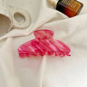 Pink marble texture hair claw clip made of acetate fiber on a white fabric background