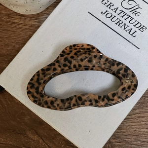 French handmade acetate hair claw clip with tortoise shell pattern on a book