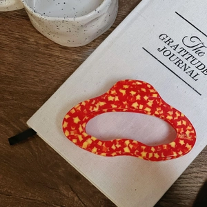 Red cloud hair claw with yellow stars and France Handmade text on white notebook