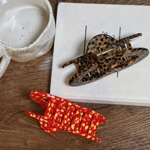 Detail of leopard print and red floral hair claw clips on a white book and wooden table