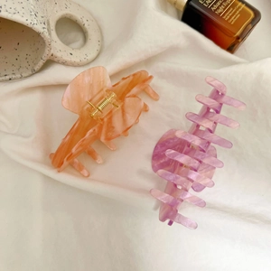 Detail of marble pattern hair claw clips in peach and lavender on white cloth