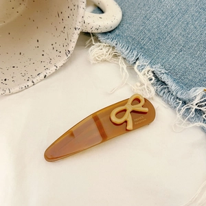 Brown translucent bow hair clip with France Handmade logo on a lifestyle background