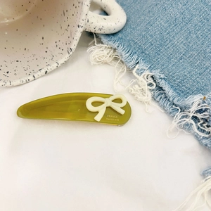 Detail view of olive green teardrop hair clip with cream bow and France Handmade logo