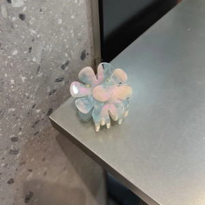 Dettaglio della pinza per capelli a fiore con finitura perlata e riflessi aurora