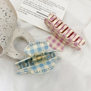 Close-up of checkered claw clips with crystal flowers on a soft white background