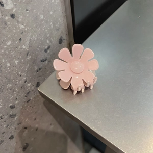 Dettaglio della molletta per capelli a fiore rosa con finitura opaca e denti di tenuta