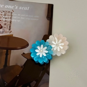 Detailed close-up of 3D layered daisy flower hair clips in blue and white colors
