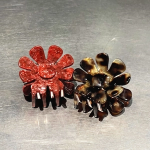 Dettaglio macro di due mollette per capelli a fiore in acetato con motivi marmorizzati