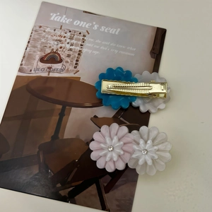 Close-up of cute daisy acetate hair clips with rhinestones and gold metal duckbill clips