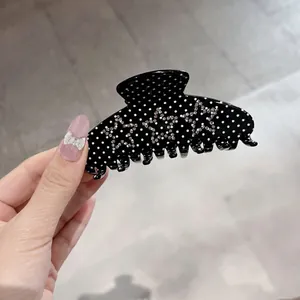 Black large hair claw clip with white polka dots and silver rhinestone star decorations