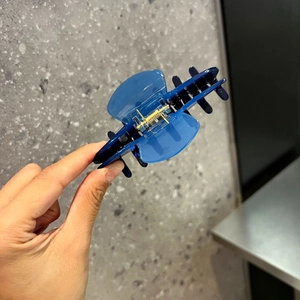 Detaillierte Nahaufnahme einer blauen transparenten Haarklammer mit goldener Metallfeder