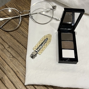 Three-color brow powder and eyeshadow palette in black case with mirror on fabric background
