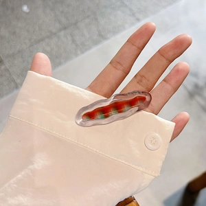 Pince à cheveux ondulée translucide avec motifs à carreaux colorés tenue à la main