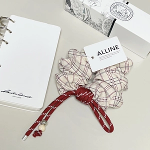 Chouchou élégant à carreaux abricot avec cordon rouge et perles sur fond minimaliste